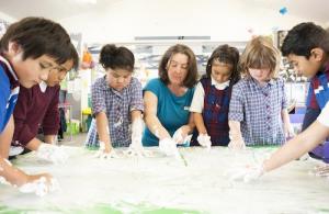 Children finger painting at a table.