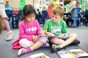 Two children drawing on paper together.